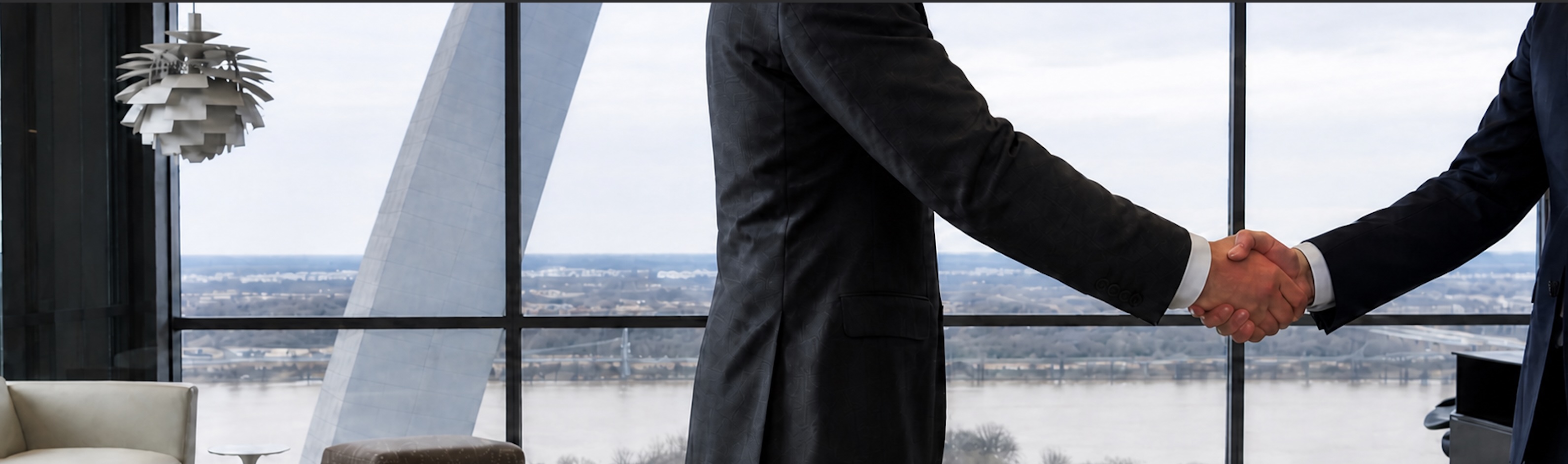 Two business professionals shaking hands in a modern office overlooking a river